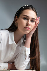 Young woman with dark hair in white long sleeve blouse isolated on grey portrait