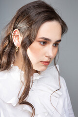 Portrait of young woman with long hair with dark brown eyes isolated on grey in white blouse