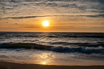 Obraz premium Waves breaking onto the shore at sunrise