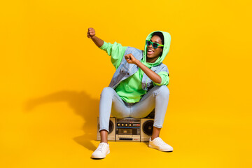 Full body photo of funny youngster sitting boom box enjoy have fun isolated on yellow color...