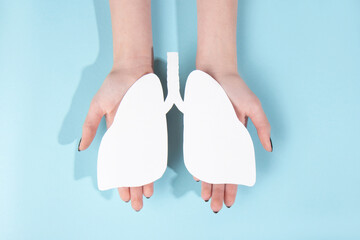 Human hold model of a human lungs made of white paper on a blue background. World kidney day