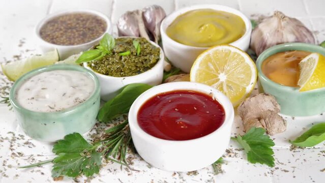 Assortment of different classic sauces and dips in sauceboats. Mayonnaise, ketchup, tartare, mustard, pesto, sour cream, barbecue sauces with spices, herbs, lemon
