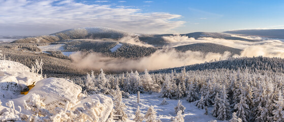 Through the valleys, the fog climbs the snow-capped mountain range of the Snieznik Massif just...