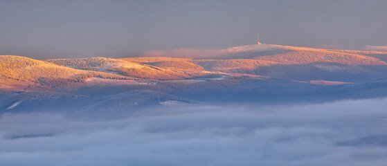 Czech mountain range High Jesenik with the highest peak of Praded immersed in the fog at sunset, view from the Polish peak of Czarna Gora in winter. - obrazy, fototapety, plakaty