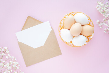 Happy easter natural eggs in nest, craft envelope and flower decoration on pink background. Flat lay, mockup, Place for text