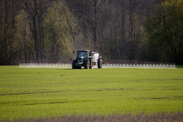 Sprayer on a green crop field in spring.