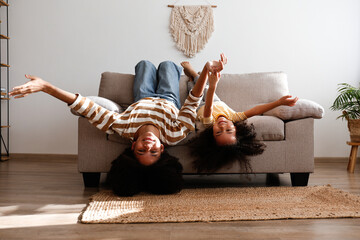 Younger and older sister spending time together at home. Two black girls of different age messing...