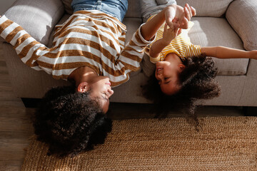 Younger and older sister spending time together at home. Two black girls of different age messing...