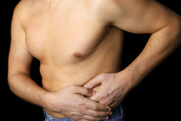 Man with side pain on black background. Shirtless person suffering from kidney, stomach or pancreas inflammation