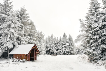 Winter landscape in the Polish mountains of the Sudetes, a snow-covered tourist shelter on a mountain hiking trail, a place to rest on a cloudy, foggy day.