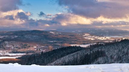 Winter landscape in the Polish mountains of the Sudetes, a panorama from the Klodzka Gora observation tower to the Snieznik Massif mountain range at sunset.