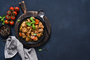 Stew with spices, tomatoes and carrots on a concrete cheno background.