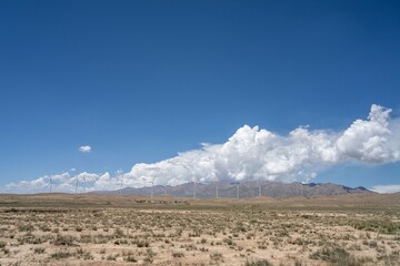 Some wind power facilities in the desert under blue sky and white clouds - obrazy, fototapety, plakaty