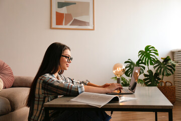 Online education concept. Young beautiful brunette woman typing on her laptop. Portrait of female college student studying at home. Close up, copy space, background.