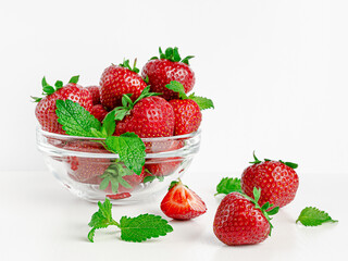 Fresh strawberries and mint in transparent glass bowl on white background. Copy space