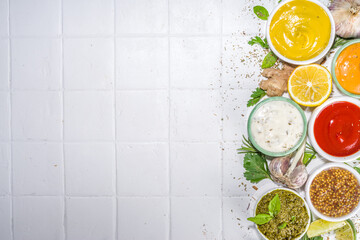 Assortment of different classic sauces and dips in sauceboats. Mayonnaise, ketchup, tartare, mustard, pesto, sour cream, barbecue sauces with spices, herbs, lemon