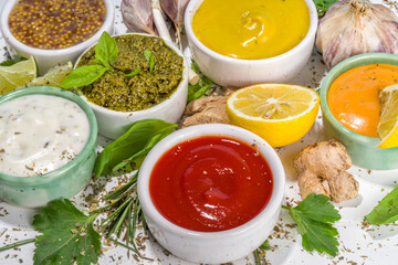 Assortment of different classic sauces and dips in sauceboats. Mayonnaise, ketchup, tartare, mustard, pesto, sour cream, barbecue sauces with spices, herbs, lemon