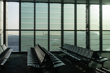 a deserted airport, empty benches by a panoramic window, a huge plane visible through the glass walls of an interchange hub in the United Arab Emirates