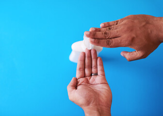 An overhead shot of a man dispensing soap against a blue background