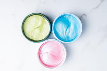 Various facial eye patches in jars. Hydrogel patch. Anti aging and lifting treatment. Face skin care. Hydrating and wrinkles patch. Top view. Modern cosmetic concept.