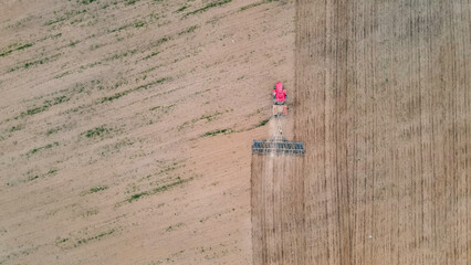 Aerial view of a tractor working in the field. Dust and endless plowed field