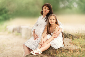 Pregnant mother with her daughter in nature.