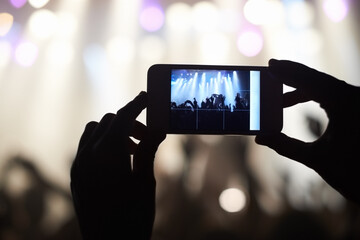 A person filming their favourite band with a camera phone. This concert was created for the sole...
