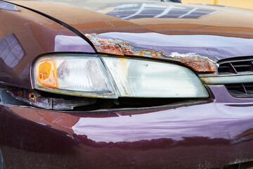 headlight of a rusty old car of burgundy color close-up
