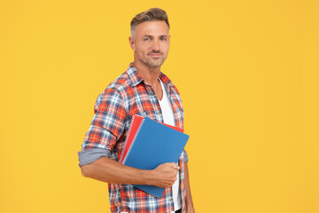 Happy man teacher holding school books yellow background, education