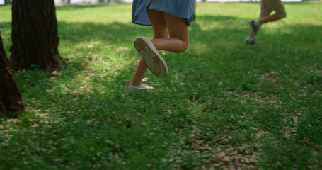 Unrecognized kid legs run on green lawn. Happy children play on fresh grass.