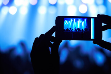Fototapeta na wymiar Cropped shot of a person filming their favorite band with a camera phone. This concert was created for the sole purpose of this photo shoot, featuring 300 models and 3 live bands. All people in this