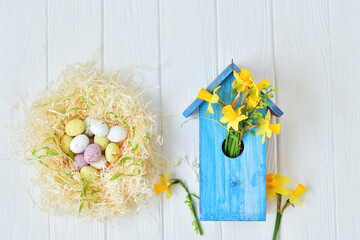 Colorful Easter eggs in nest on light wooden background.Happy Easter. Spring mood