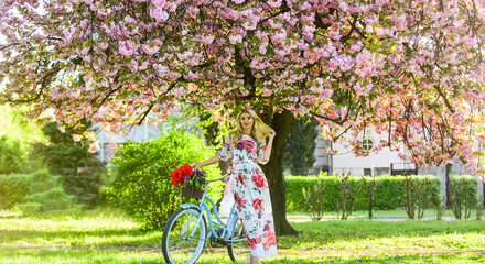 Spring mood. girl with vintage bike. blooming sakura tree. summer fashion and beauty. lady walk in...