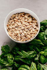 Photo of a fresh healthy ingridients like green basil, fresh garlic, roast nut, parmegiano cheese to make homemade pesto sauce on a wooden desk indoors daylight