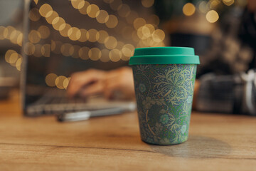 Bamboo reusable cup for coffee on table in cafe. Concept of zero waste takeaway mug 