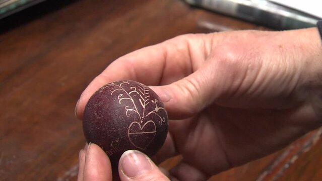 woman holds old hand painted easter egg with ornaments and written verses in hand