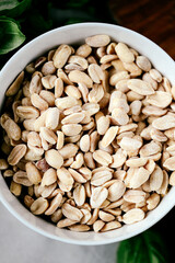 Photo of a fresh healthy ingridients like green basil, fresh garlic, roast nut, parmegiano cheese to make homemade pesto sauce on a wooden desk indoors daylight