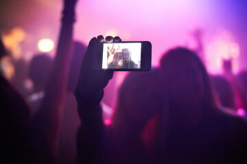 Shot of a fan filming a concert on their camera. This concert was created for the sole purpose of this photo shoot, featuring 300 models and 3 live bands. All people in this shoot are model released.