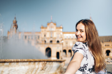 Beautiful smiling young woman holds the viewer's hand sightseeing in Europe. Follow me travel concept.