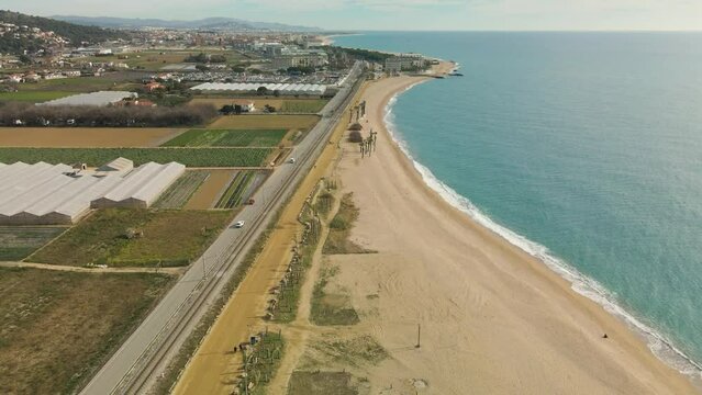Aerial view with drone of Pineda de Mar and Malgrat de Mar beach in Barcelona Spain Costa del Maresme cultivation fields with greenhouses beachfront