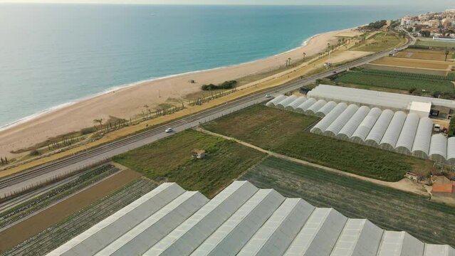 Aerial view with drone of Pineda de Mar and Malgrat de Mar beach in Barcelona Spain Costa del Maresme cultivation fields with greenhouses beachfront