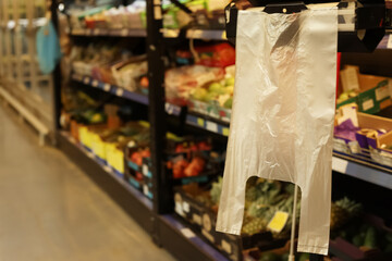 Plastic bags near rack with fruits in supermarket, space for text