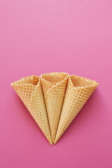 three waffle cones on a raspberry background