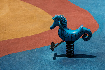 Seahorse shape bouncy spring rider on sunny summer day on colorful kids playground