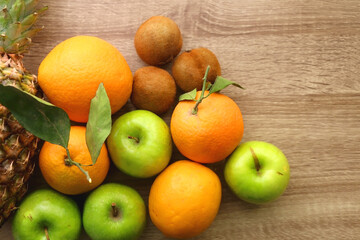 Pineapple, apples, oranges, lemons and kiwis on a wooden table. Top view.