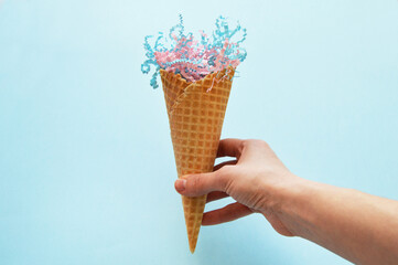 waffle cone in hand with paper filling on a blue background