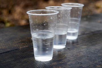 three plastic glasses with water