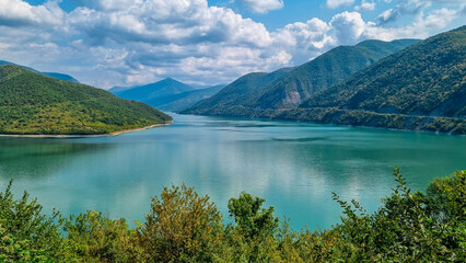 Fototapeta na wymiar Zhinvali Reservoir. Beautiful mountain landscape. Ananuri lake with turquoise colored water surrounded by the Central Caucasus mountain ranges, Kazbegi Region in Georgia.Military road to Stepantsminda