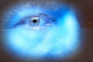 Light beams eminate from a close up of a mans eye with blue glow
