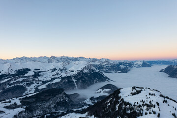 Amazing sunrise with red sky and a beautiful landscape in the wonderful region in Switzerland called Mythenregion. Beautiful mountain called Mythen and an epic sea of fog in the background.